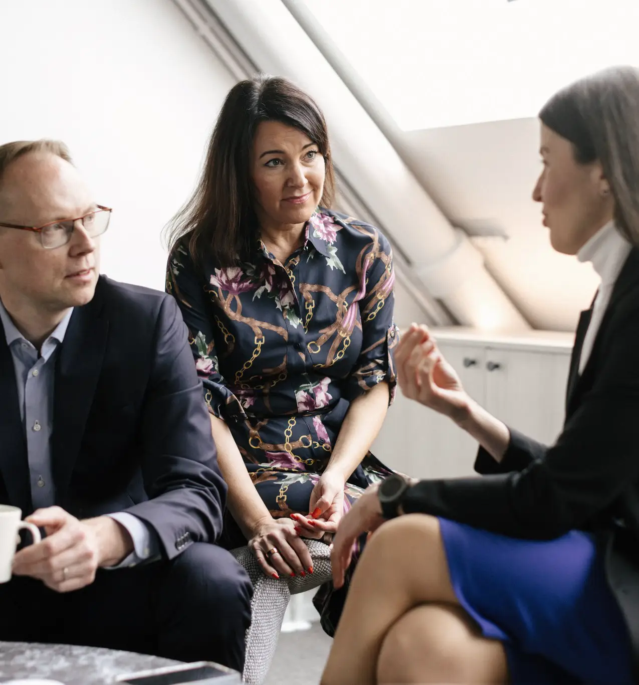 a man and two women sitting around a table discussing