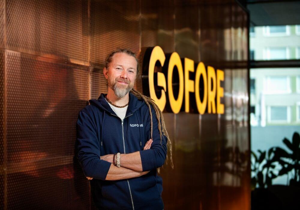 Man posing in front of Gofore illuminated logo wall.