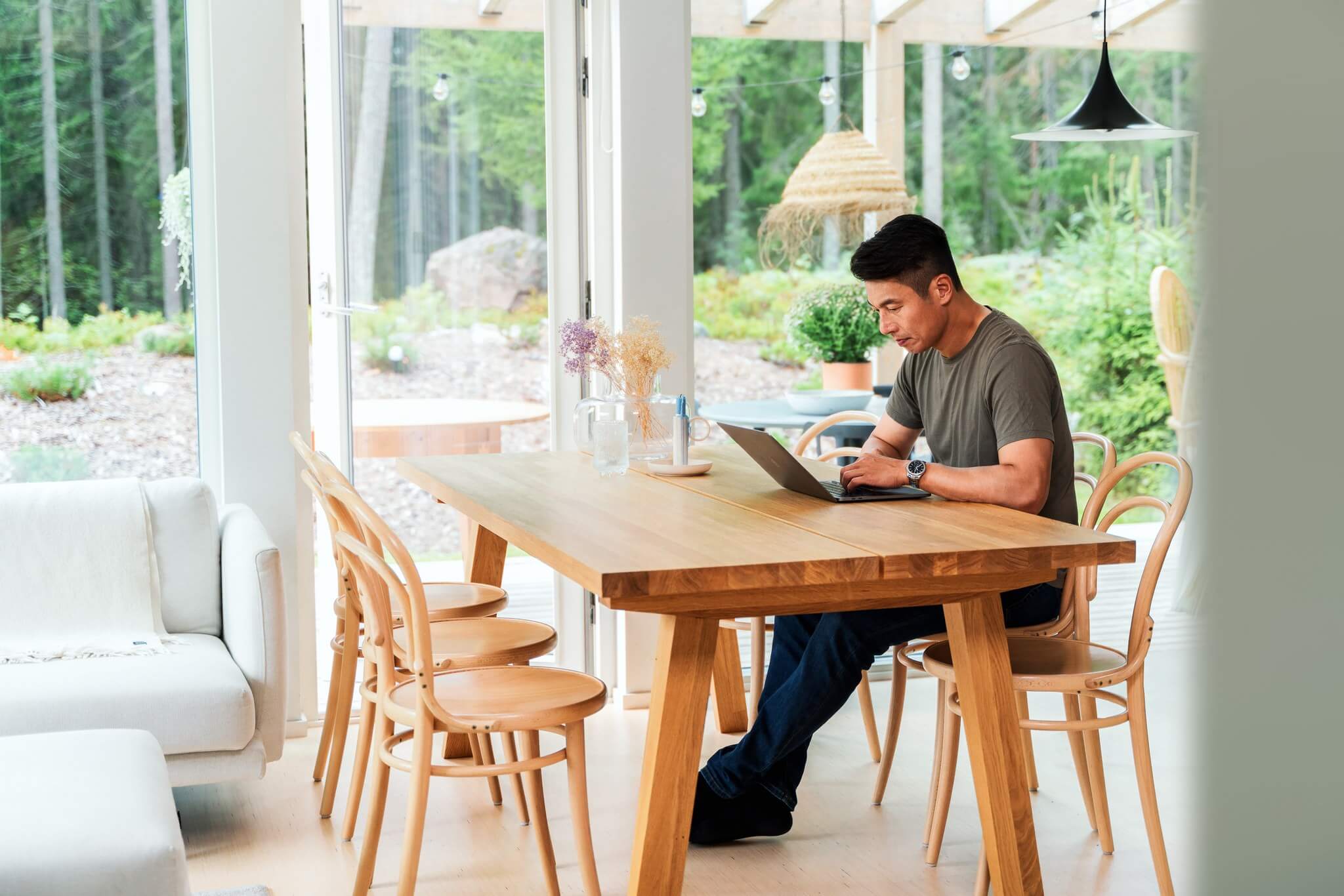 Man typing at a kitchen table looking at a laptop.