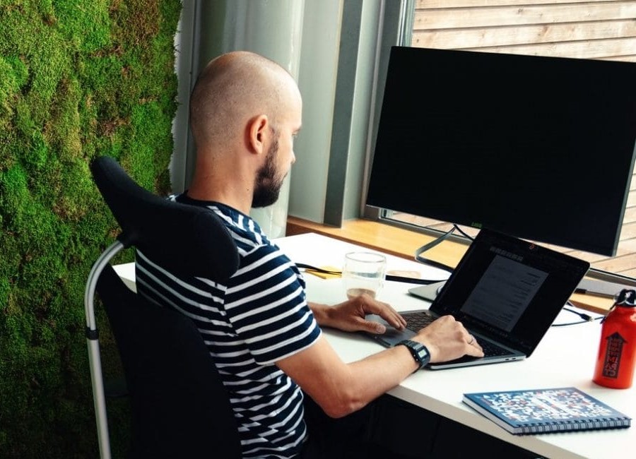 Person sitting in front of a laptop and typing in an office environment.