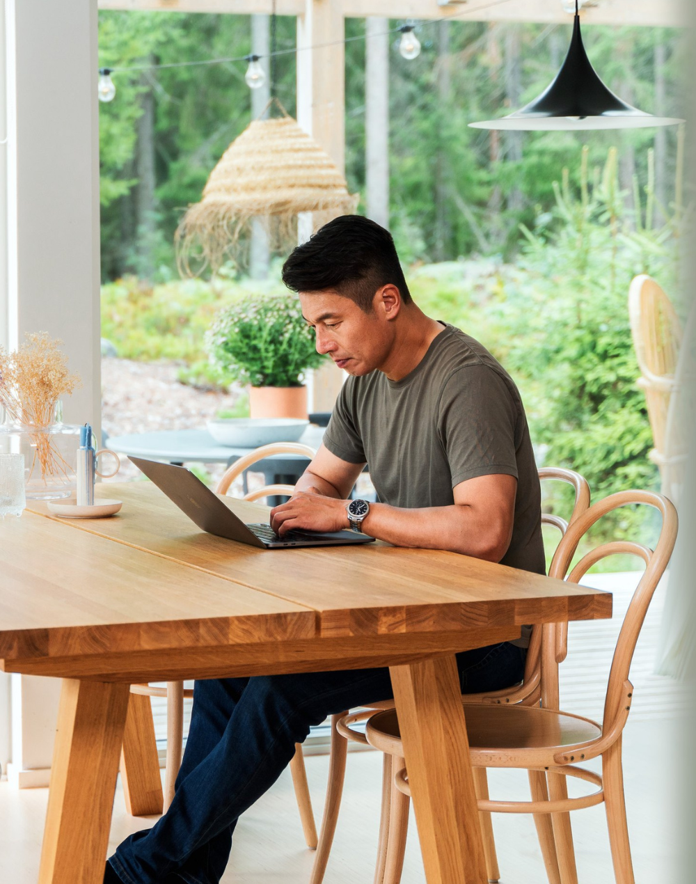 A person looking at a laptop by a dinner table.