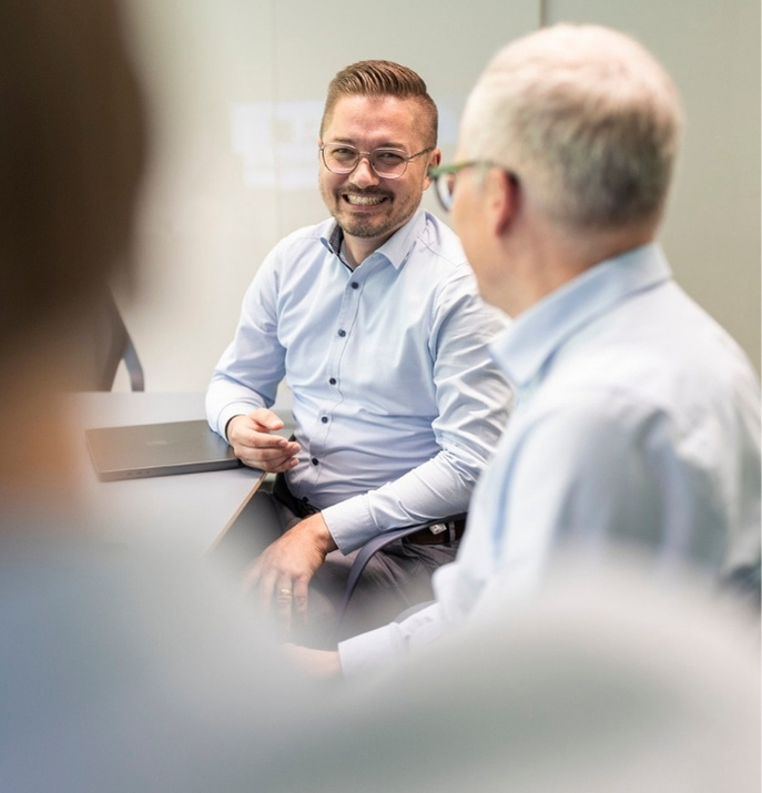 two men sitting by meeting room table with friendly faces